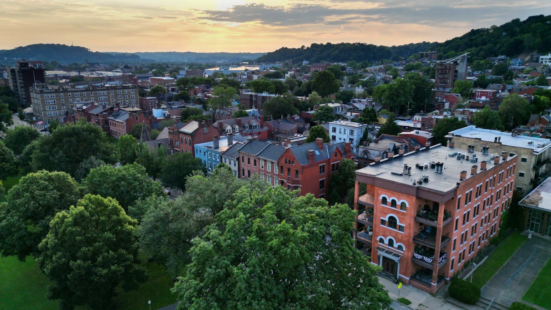 Rooftops and mature tree cover across a dense Pittsburgh-area neighborhood at sunset